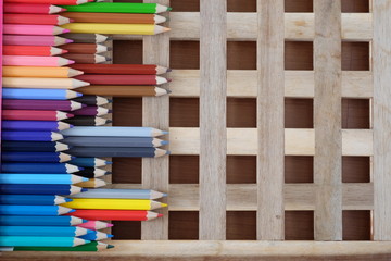 Colorful pencils on crossing of wooden background