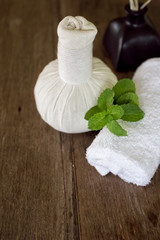 Obraz na płótnie Canvas Thai herbal compress, white towel and mint on wooden table