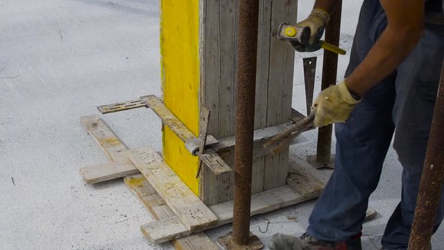 worker reinforces the wooden formwork with steel ties
