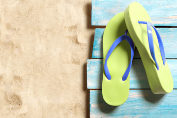 Yellow flip flop on blue wooden boards on the sand beach
