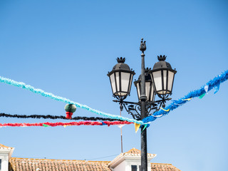 Vintage style black metal lampost with opaque glass decorated for a festival, with bunting, in Portugal, Vila Real de Santo Antonio.