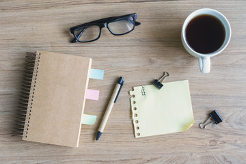 Cup of coffee with blank notebook and notepaper on wooden desk