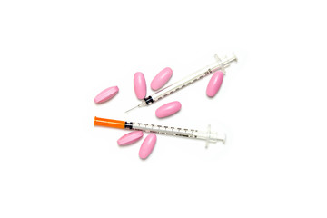 Medical syringe and pink pills isolated on white background