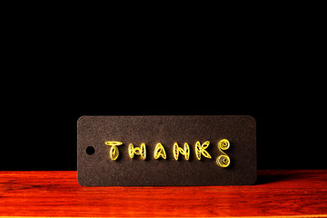 A Thanks Card on a Wooden Table with Black Background