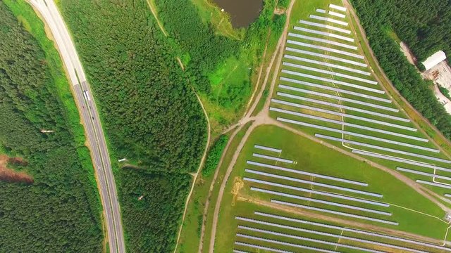 Camera flight over a solar power plant in agricultural landscape. Industrial background on renewable resources theme. Industry of power and fuel generation in European Union.