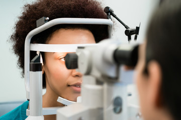 Frau beim Augen Vermessen mit Refraktometer bei Optiker oder Augenarzt