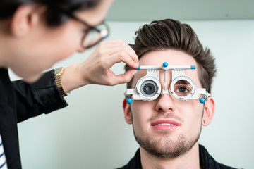 Optiker und Mann bei Augentest mit Phoropter
