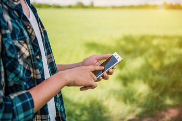 closeup of a young man using a smartphone in a natural landscape, with a meadow in the background - 114377485