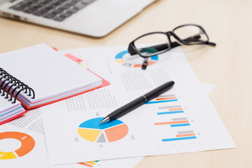 Office workplace with laptop, reports and pencils