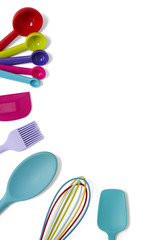 Cooking utensils - a selection of colorful silicone baking spoons, spatulas, whisk, measuring spoons and a pastry brush isolated on a white background forming a baking themed page border