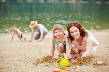 Eltern spielen mit Kindern im Sand