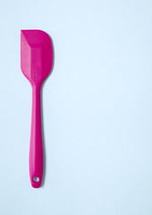 Cooking utensils - a pink silicone baking spatula on a blue background forming a page border