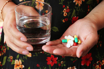 the young woman holds in hands pills and glass of water