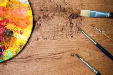 Artist paint brushes and palette on wooden background