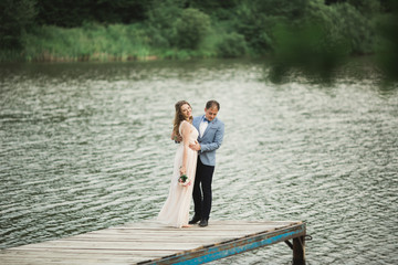 Elegant beautiful wedding couple posing near a lake at sunset