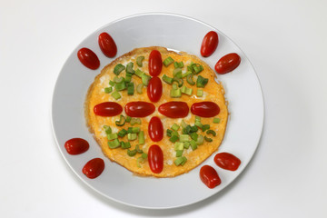 Omelette with cherry tomatoes and green onion, top view, isolated on white background