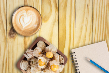 cape gooseberry in bowl wooden, vintage book, blue pencil and la