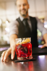 Barman is making cocktail at night club.