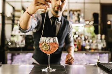 Barman is making cocktail at night club.