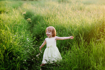 Naklejka na ściany i meble Outdoor portrait of a cute little girl playing in the grass, childhood, happiness, nature, relaxation