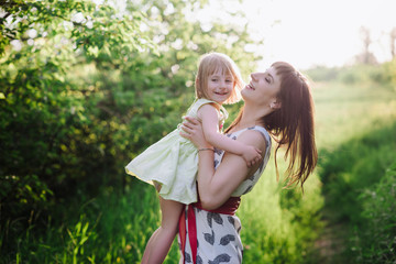 Mom kisses and hugs daughter on nature, family, motherhood, child