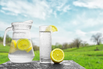 Fresh cold water with lemon and ice in a pitcher on the table.Homemade lemonade with fresh citruses...