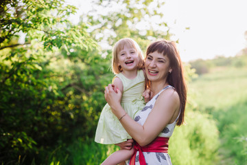 Fototapeta premium Mom kisses and hugs daughter on nature, family, motherhood, child