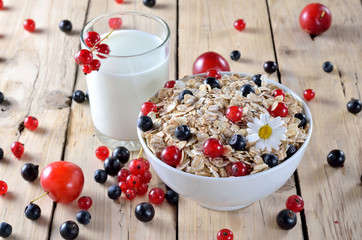 Oatmeal with berries and a glass of fresh milk on a wooden table