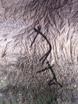 Art in sandstone cave. Black carbon paint of human hunting