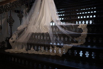 Train wedding dress lying on the iron stairs