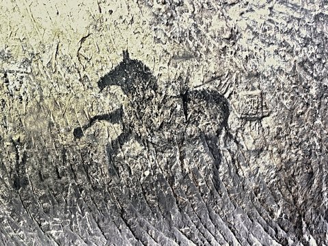 Abstract children art in sandstone cave. Black carbon paint of horses on sandstone wall, copy of prehistoric picture.