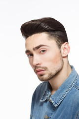 Fototapeta premium Portrait of handsome man in jeans shirt demonstrating modern hairstyle concept in studio. Male with bright black hair. Hairdressing concept. Studio shot.