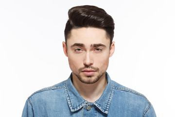 Fototapeta premium Portrait of handsome man in jeans shirtshowing his modern hairstyle isolated on white background. Male with short black hair in studio.