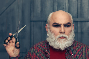 old man cutting beard with scissors
