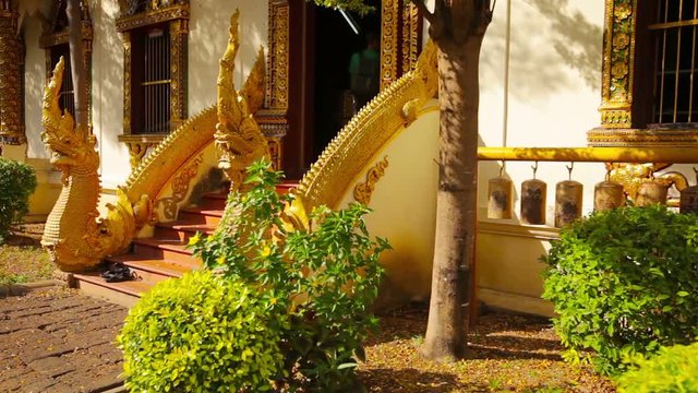 Video FullHD - Traditional, ornate, dragon sculptures flank the main steps leading to the entrance of a Buddhist temple in Southeast Asia.