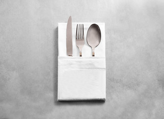 Blank white restaurant cloth napkin mockup with silver cutlery set, isolated. Knife fork and spoon...