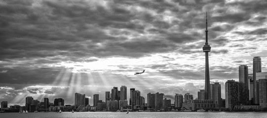 TORONTO SKYLINE IN BLACK AND WHITE WITH SUNBEAMS AND AN AIRPLANE IN THE BACKGROUND 