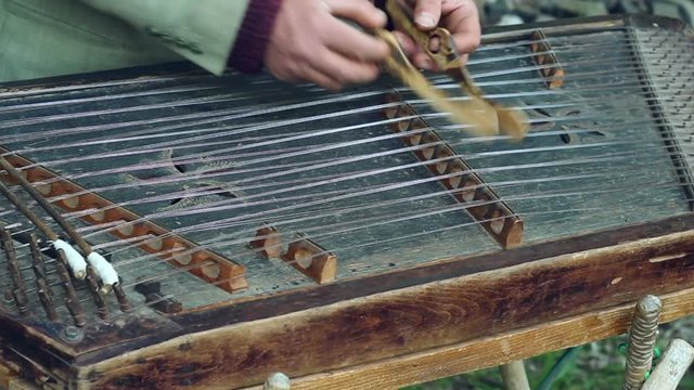 Musician play on traditional cimbalom. Musical instrument. Traditional music instrument. Man fingering string cimbalom instrument with sticks. Dulcimer music stringed by musician. Acoustic folk sound