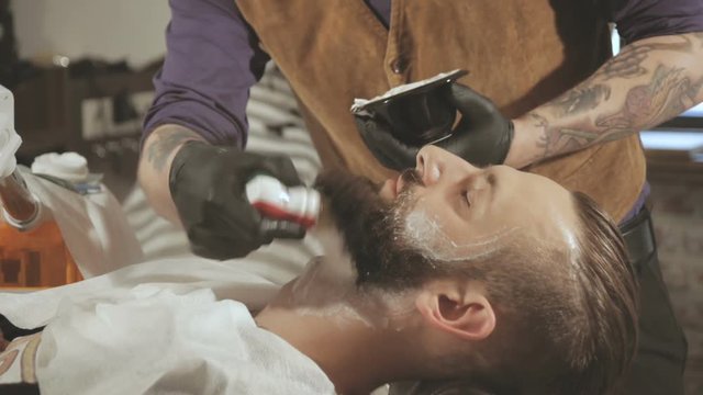 Client during beard shaving in barber shop