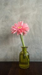Gerbera flower in bottle on table with loft background, home decoration with bottle of flower