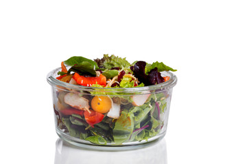 Fresh mixed salad in glass container isolated on white 