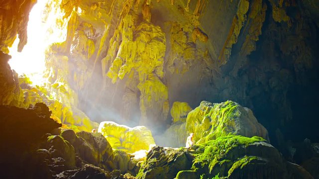 Video 1080p FullHD - Tourist examining the moss that is growing on rocks at the sunny mouth of a natural cave called Tham Phu Kham in Vang Vieng, Laos.