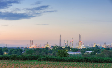 Oil refinery plant on agriculture field at dusk.