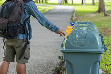 Male hand throwing empty plastic bottle into the trash.