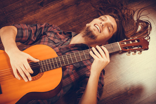 Smiled male with wooden guitar.
