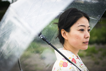 Young attractive Japanese woman in kimono holding an umbrella on a rainy day
