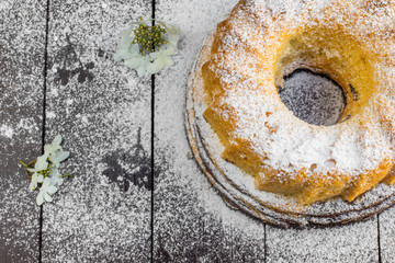 Top View on Bundt Cake with Sugar and Flower on a Dark Wood Tabl