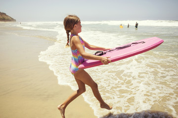 Cute little girl playing at the beach on summer vacation