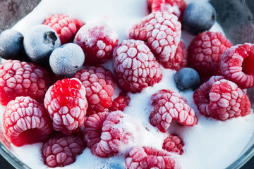 Frozen raspberry and blueberry with ice cream in a glass bowl