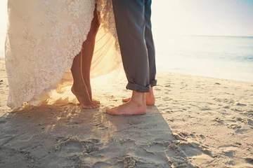 Fotobehang Bride and groom are standing at the beach © smeshkovam
